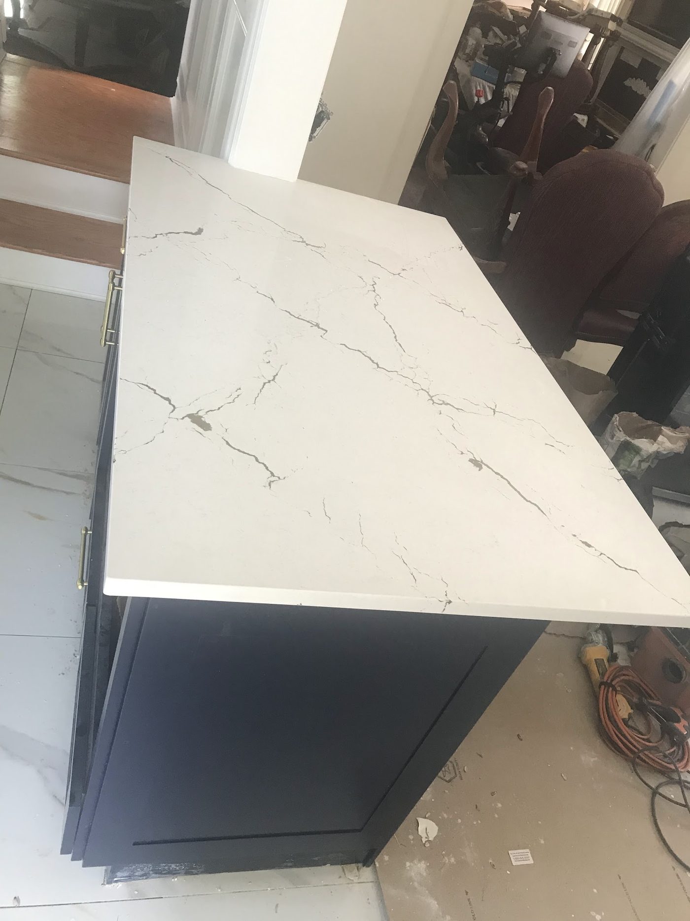 A navy blue cabinet base topped with a white quartz countertop with grey veining, during installation.