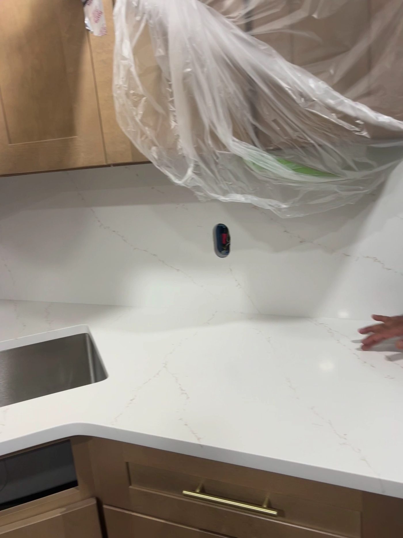 A white quartz countertop with a matching full-height backsplash above natural wood shaker cabinets.